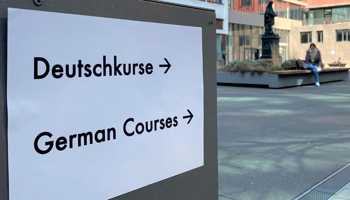 zur Vergrößerungsansicht des Bildes: Schild hängt an der Tür zum Hörsaalgebäude mit der Aufschrift "Deutsch-Kurse" auf Deutsch und Englisch.