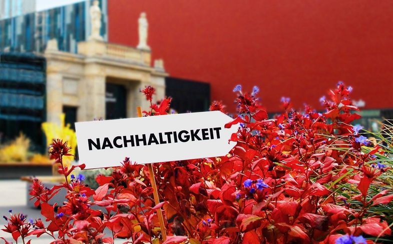 Zu sehen ist das Leibniz-Forum der Universität Leipzig, im Vordergrund ein Schild mit der Aufschrift "Nachhaltigkeit".