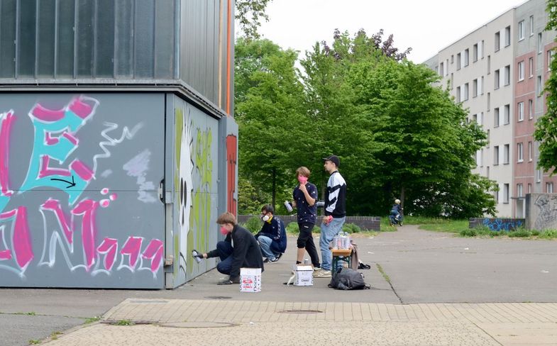Jugendliche besprühen eine Wand mit Graffiti