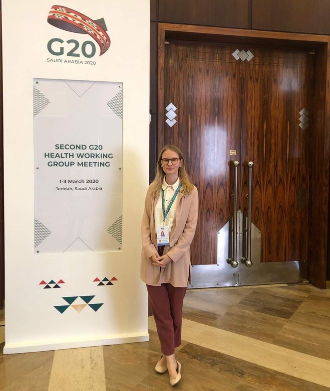 Zu sehen ist Inga Wilke vor einem Schild des G20-Gipfels