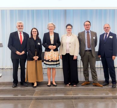 Drei Länder, ein Unibund (v.l.): Prof. Dr. Armin Willingmann (Wissenschaftsminister Sachsen-Anhalt), Prof. Dr. Heike Graßmann (Staatssekretärin im SMWK), Prof. Dr. Eva Inés Obergfell (Rektorin Universität Leipzig), Prof. Dr. Claudia Becker (Rektorin Eine Gruppe von sechs Personen vor einem hellen Vorhang, nebeneinander stehend.