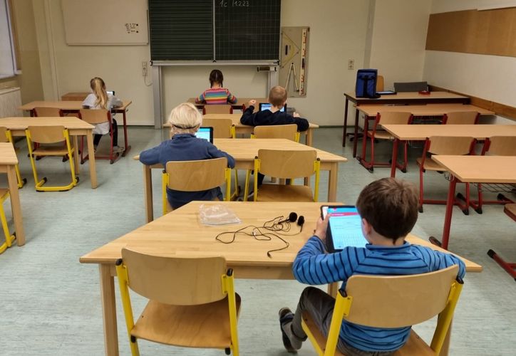 Das Foto zeigt ein Klassenzimmer, in dem Kinder mit Tablets lernen.