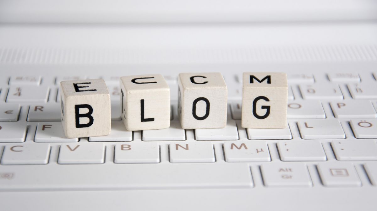 Würfel mit Buchstaben, die das Wort "Blog" bilden, liegen auf einer flachen Computertastatur