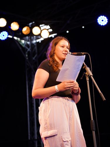 Elisabeth Neumann am Mikrofon mit einem Textblatt in der Hand
