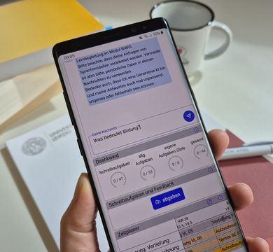 Die digitale Mentoring Workbench mit Chatbot begleitet Studierende in den Bildungswissenschaften, Foto: Nina Vogt Hand hält ein Smartphone, auf dem der Chatbot zu sehen ist. Die eingetippte Frage lautet: "Was bedeutet Bildung?"
