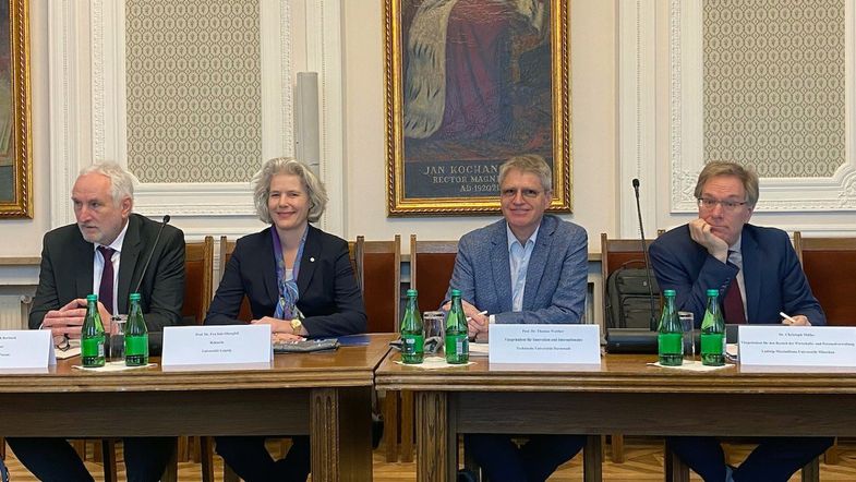 Vier Menschen, darunter die Rektorin, an Tischen sitzend, im Senatssaal der Universität Warschau.