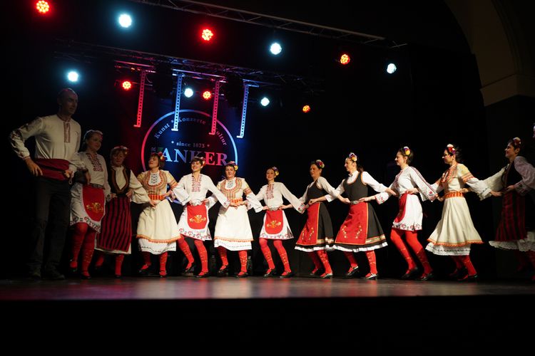 Tänzerinnen und Tänzer auf der Bühne in rot-weißen bulgarischen Trachten beim Bulgarischen Volkstanz