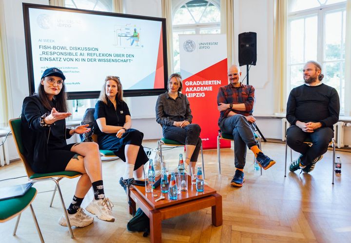 Zu sehen sind fünf Diskutierende in einer Stuhlreihe auf dem Podium