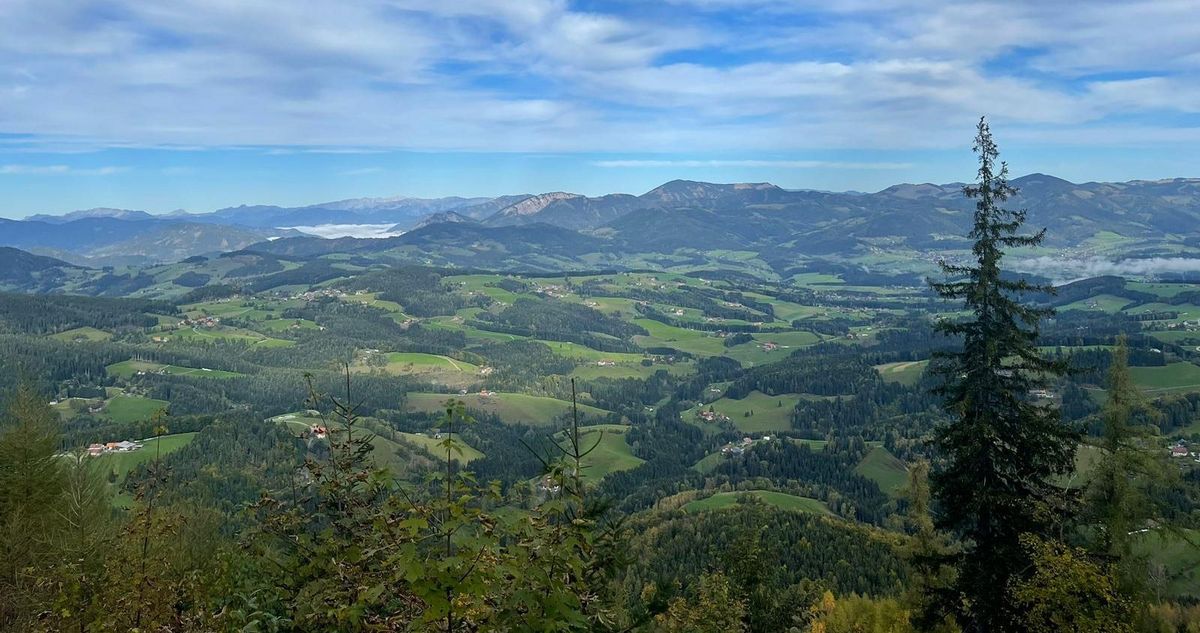 zur Vergrößerungsansicht des Bildes: Zu sehen ist ein Blick von einem Berg über ein Tal hin zu den Bergen der Alpen in der Steiermark