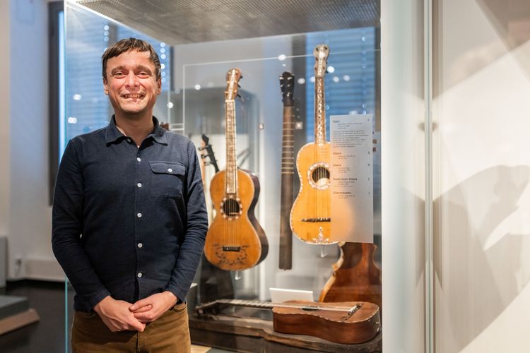 Auf dem Bild ist Stefan Hindtsche im Musikinstrumentenmuseum mit der ältesten bekannten sächsischen Gitarre aus dem Jahr 1801 zu sehen.