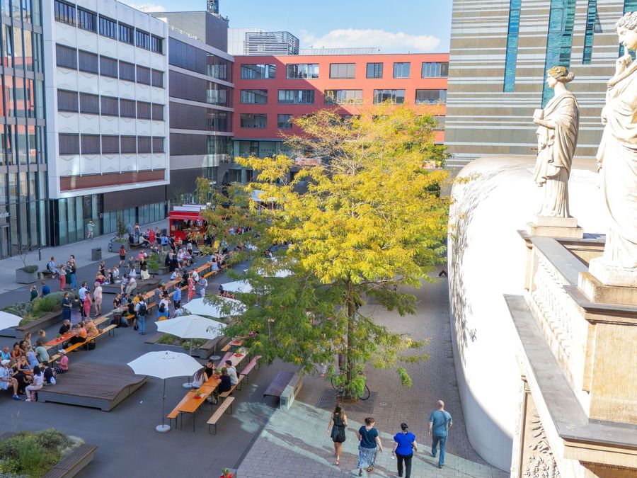 zur Vergrößerungsansicht des Bildes: Blick ins Leibnizorum von oben. Zu sehen sind Menschen an langen Holztischen.