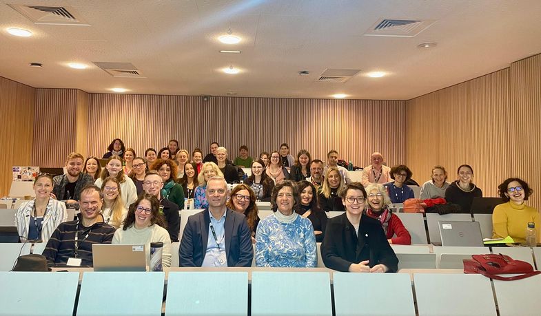 Zu sehen ist ein Gruppenbild der Teilnehmenden an der Staff Week. Die rund 20 Teilnehmenden sitzen in einem Hörsaal.
