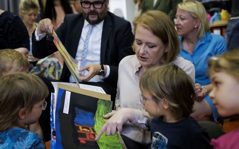 Auf dem Bild schauen sich Bundesfamilienministerin Lisa Paus und Sachsens Kultusminister Christian Piwarz - umringt von Kindern - Bilder der Kleinen an.