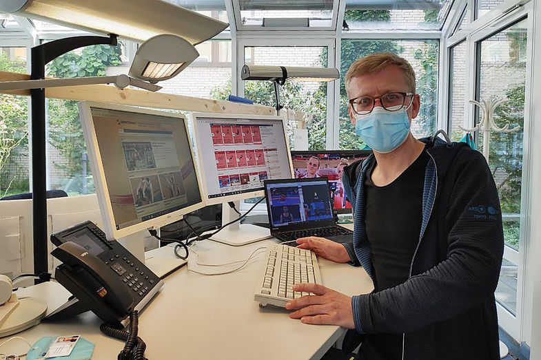 Zu sehen ist Dirk Hofmeister am Arbeitsplatz vor mehreren Monitoren