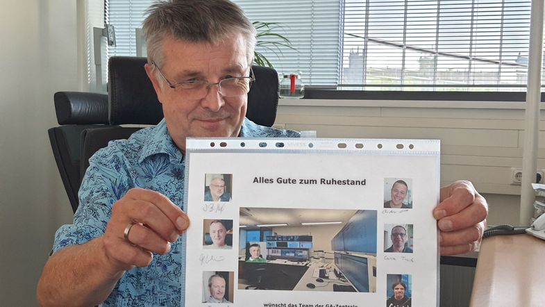 Auf dem Bild ist Ulrich Gasch mit einer Fotocollage zu sehen, die ihm seine sechs Kollegen zum Abschied geschenkt haben.