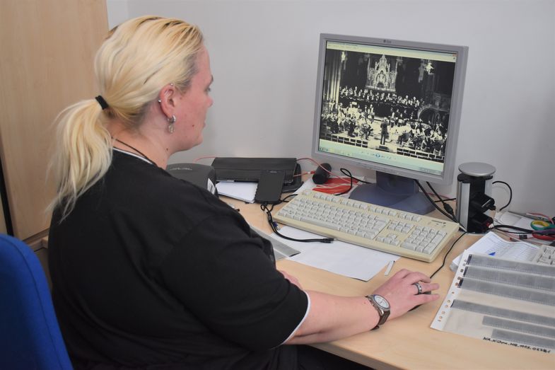 Frau sitzt am PC und betrachtet digitalisierte historische Dokumente