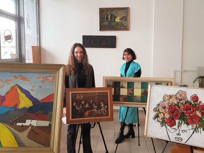 Zwei Studentinnen stehen zwischen Staffeleien mit Gemälden