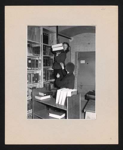 Zu sehen sind zwei Mitarbeiterinnen beim Sichten und Verpacken von Büchern im Luftschutzkeller.