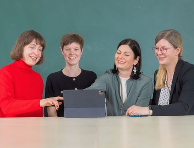 Doreen Klein, Agnes Berbée, Konstanze Pabst und Kamilla Skudelny sitzen nebeneinander an einem Tisch und blicken auf einen Bildschirm.