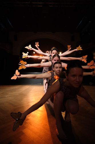 Tänzerinnen auf der Bühne mit Schmetterlingsfiguren an den Händen beim Barre au Sol