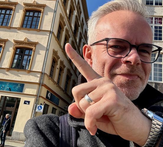 Autor Tore Renberg steht auf dem Leipziger Marktplatz und zeigt auf einen Altbau, in dem Christian Thomasius gewohnt hat.