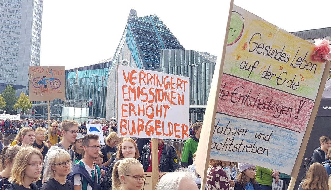Zu sehen sind Demonstranten während des Klimastreiks 2019 auf dem Augustusplatz, die Protestschilder gegen Umweltzerstörung hochhalten.