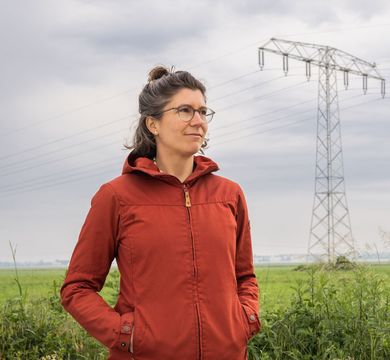 Daniela Russ vor einem Feld mit Windrad und Strommast